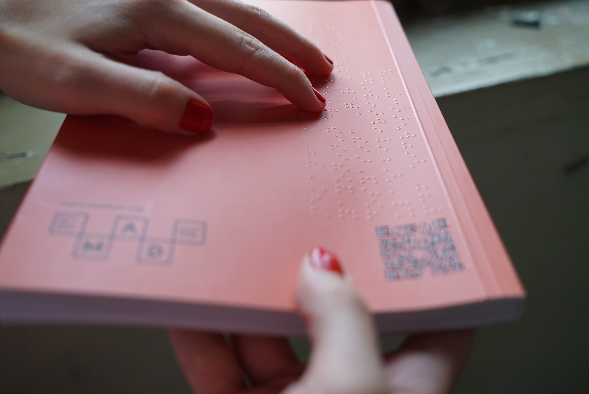 Dergiyi tutan bir çift el arka kapakta bulunan braille alfabesini okumaya çalışıyor.